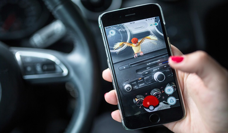 A woman plays the Pokemon Go mobile game on her smart phone in a car in Berlin on July 13, 2016. The Pokemon Go mobile gaming craze reached European fans with players in Germany the first to get their hands on the augmented reality sensation. / AFP PHOTO / dpa / Sophia Kembowski / Germany OUT